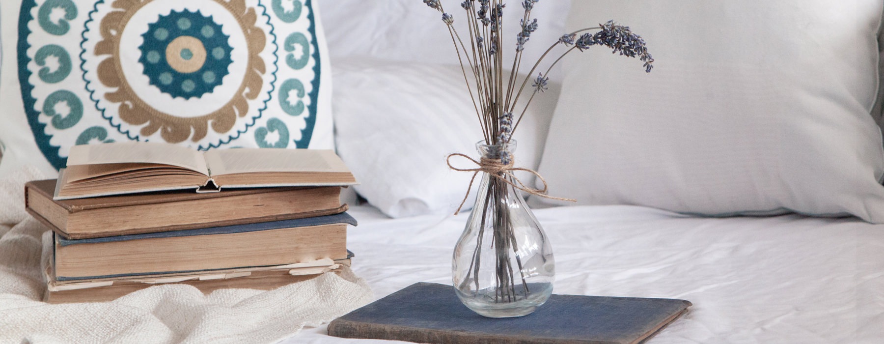 books and vase with flowers on bed